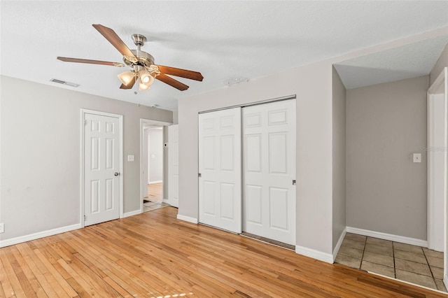 unfurnished bedroom featuring a textured ceiling, light wood-type flooring, and ceiling fan