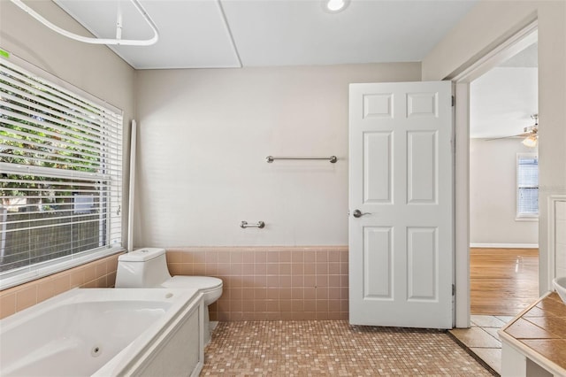 bathroom with a bathtub, ceiling fan, tile walls, tile patterned flooring, and toilet