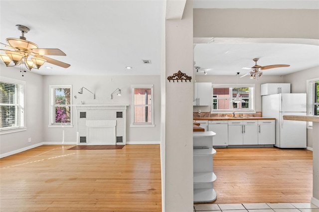 kitchen with white cabinetry, light wood-type flooring, white appliances, and a wealth of natural light