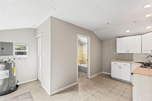 kitchen with electric panel, water heater, white cabinets, and lofted ceiling