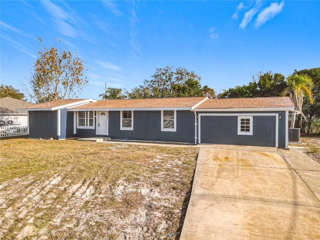 ranch-style home featuring a front lawn, cooling unit, and a garage