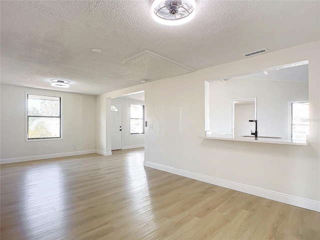 empty room featuring light hardwood / wood-style floors, sink, and a textured ceiling