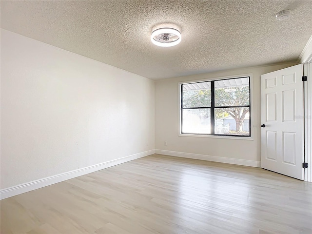 unfurnished room featuring light hardwood / wood-style flooring and a textured ceiling