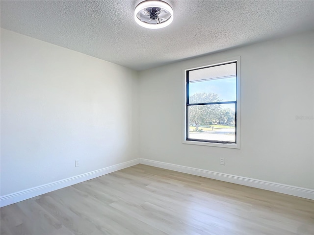 spare room featuring a textured ceiling and light hardwood / wood-style floors