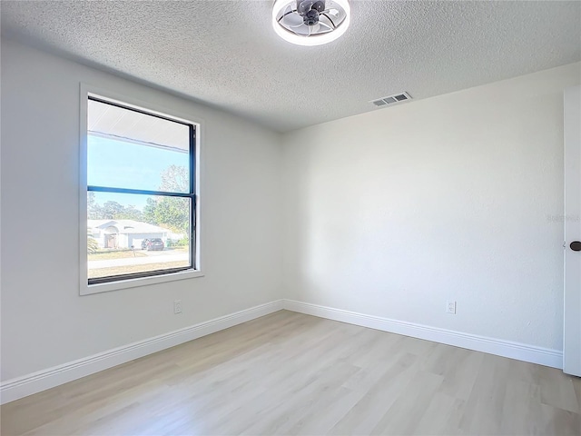 empty room featuring a textured ceiling and light hardwood / wood-style floors