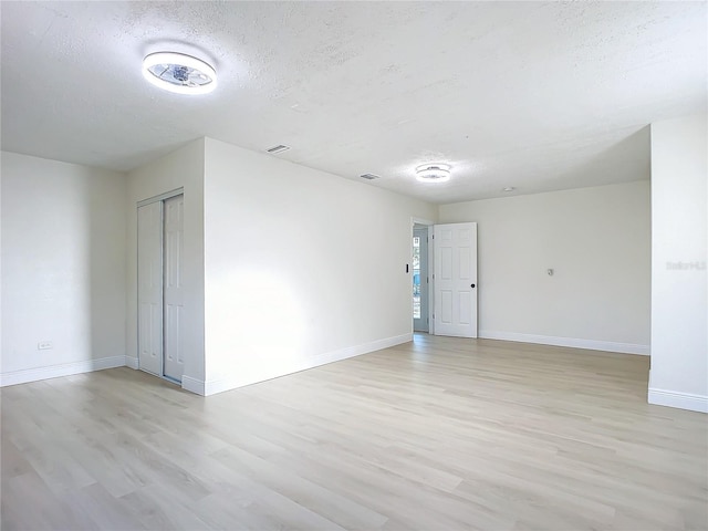 empty room with light hardwood / wood-style flooring and a textured ceiling