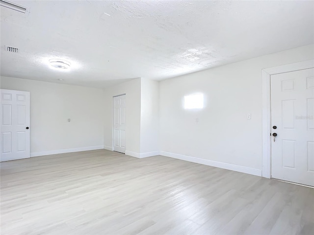 empty room featuring a textured ceiling and light hardwood / wood-style flooring