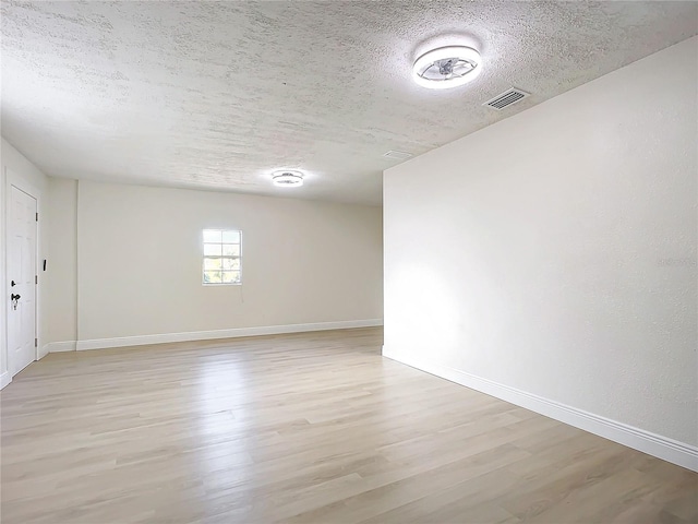 spare room featuring light wood-type flooring and a textured ceiling