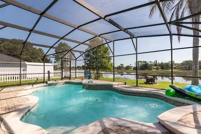 view of pool with pool water feature, glass enclosure, a patio area, and a water view