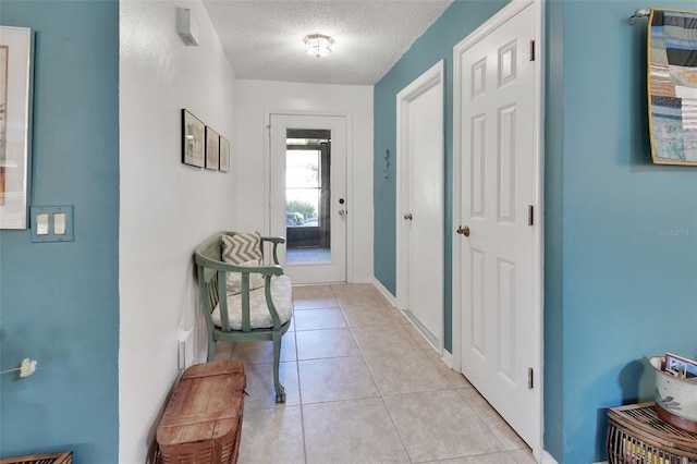 corridor featuring light tile patterned flooring and a textured ceiling