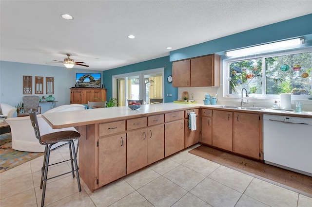 kitchen with a kitchen breakfast bar, kitchen peninsula, dishwasher, and plenty of natural light