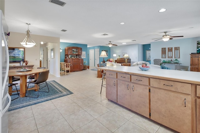 kitchen featuring a breakfast bar, ceiling fan, hanging light fixtures, and light tile patterned flooring