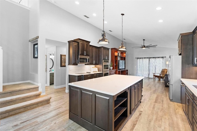 kitchen featuring ceiling fan, pendant lighting, decorative backsplash, a kitchen island, and appliances with stainless steel finishes