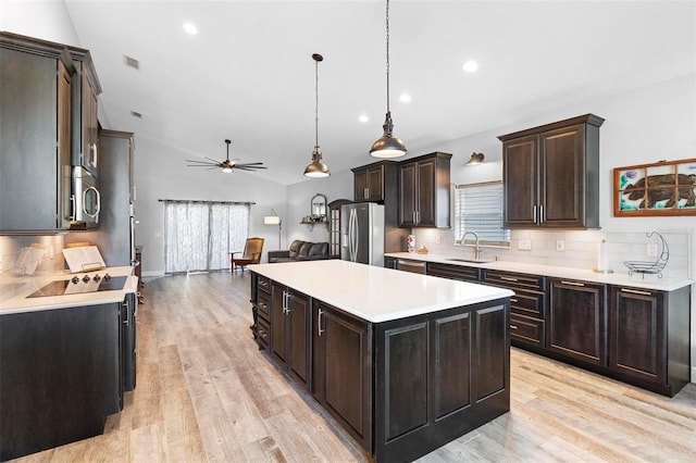 kitchen with a center island, sink, stainless steel appliances, tasteful backsplash, and pendant lighting