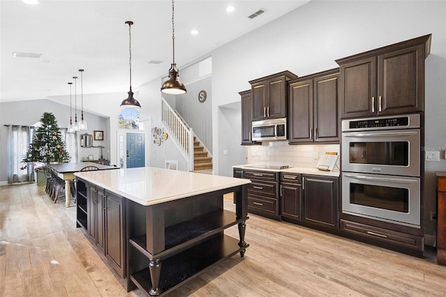 kitchen with a center island, tasteful backsplash, decorative light fixtures, dark brown cabinets, and stainless steel appliances