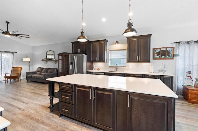 kitchen with sink, hanging light fixtures, tasteful backsplash, stainless steel fridge with ice dispenser, and lofted ceiling