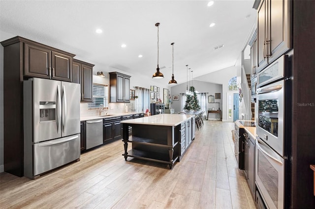 kitchen featuring appliances with stainless steel finishes, a center island, dark brown cabinetry, and pendant lighting