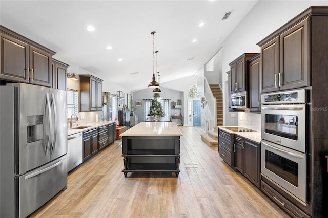 kitchen with decorative light fixtures, stainless steel appliances, a kitchen island, and tasteful backsplash