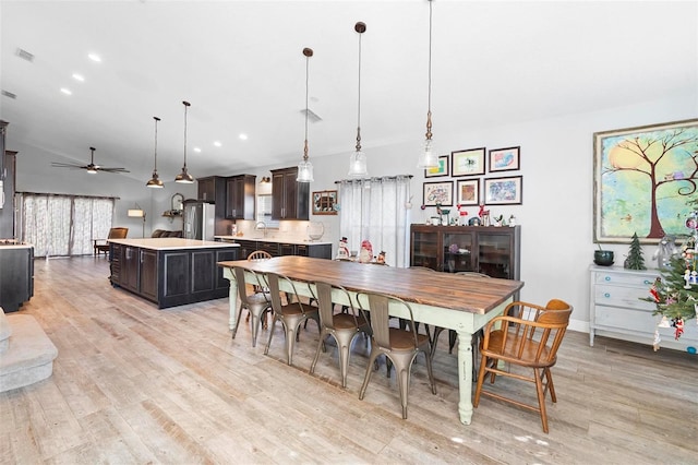 dining space featuring ceiling fan, lofted ceiling, sink, and light hardwood / wood-style flooring