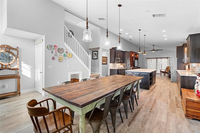 dining space with ceiling fan, sink, high vaulted ceiling, and light wood-type flooring