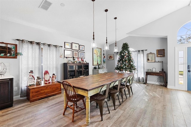 dining space with plenty of natural light, light hardwood / wood-style floors, and vaulted ceiling