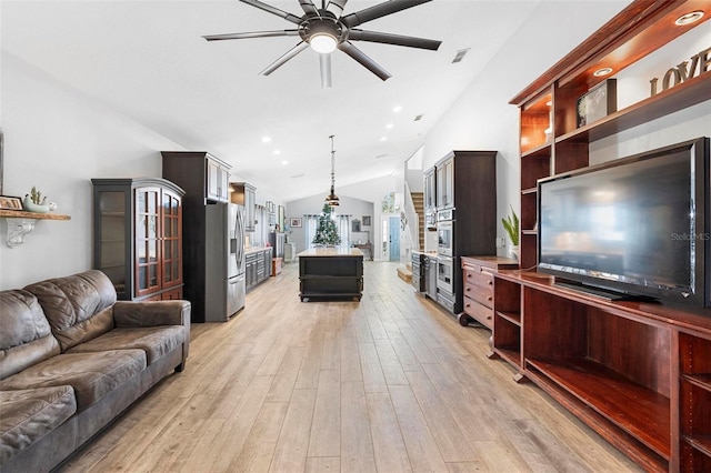 living room featuring ceiling fan, light hardwood / wood-style flooring, and vaulted ceiling