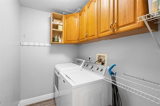 washroom featuring cabinets, hardwood / wood-style floors, washer and dryer, and a textured ceiling