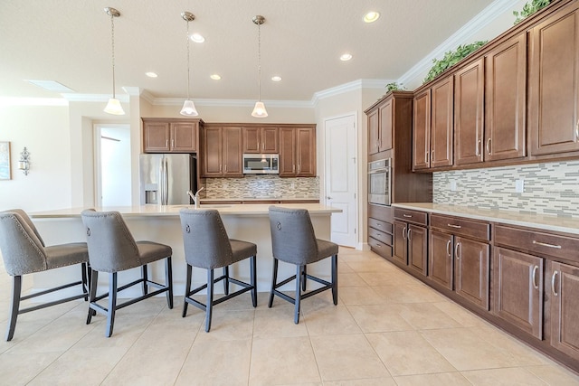 kitchen featuring decorative light fixtures, stainless steel appliances, ornamental molding, and an island with sink