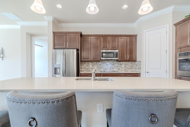 kitchen with sink, an island with sink, appliances with stainless steel finishes, and a breakfast bar area