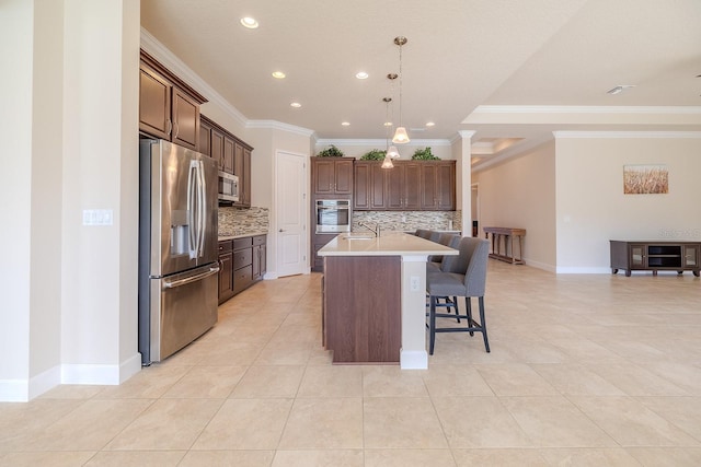 kitchen featuring a kitchen island with sink, crown molding, sink, tasteful backsplash, and stainless steel appliances