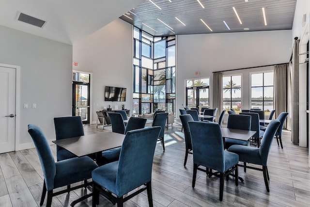 dining area with light hardwood / wood-style floors, wooden ceiling, and high vaulted ceiling