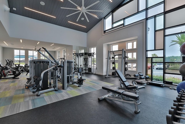 gym featuring ceiling fan, a towering ceiling, and wood ceiling