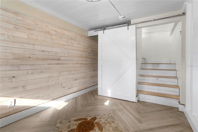 basement with wood walls, a barn door, and light parquet flooring