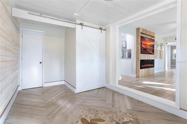 unfurnished room with a barn door, a fireplace, and light parquet flooring