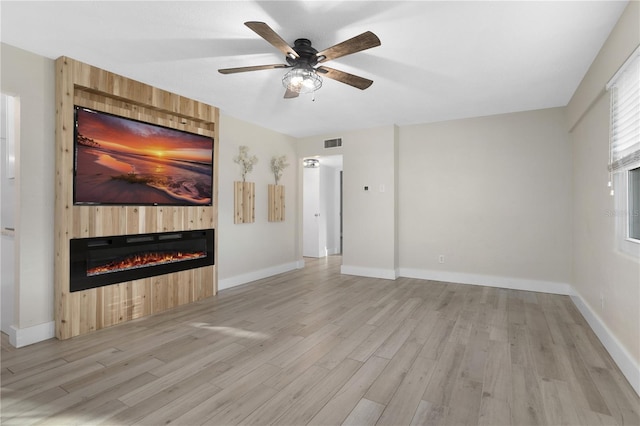 unfurnished living room with a large fireplace, light hardwood / wood-style flooring, and ceiling fan