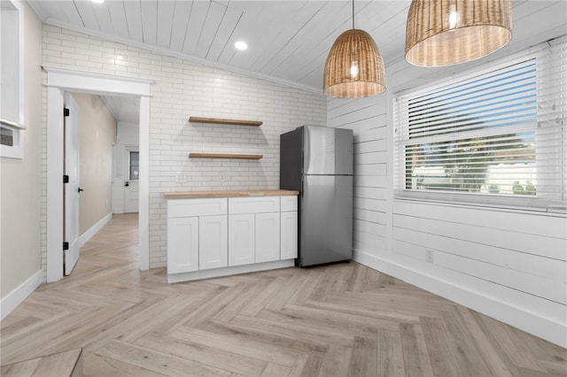 kitchen with stainless steel refrigerator, wood counters, light parquet floors, pendant lighting, and white cabinets