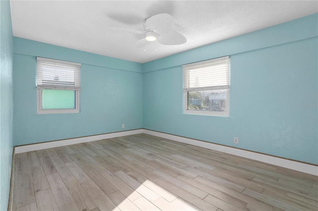 unfurnished room with ceiling fan, a wealth of natural light, and light hardwood / wood-style flooring