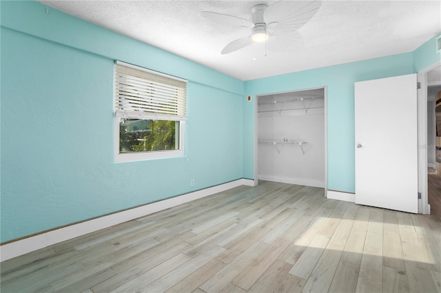 unfurnished bedroom with ceiling fan, a closet, a textured ceiling, and light wood-type flooring