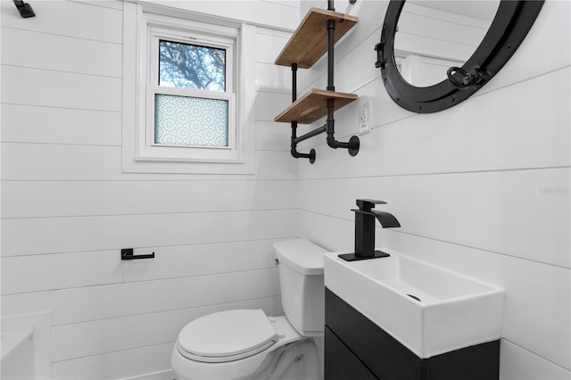 bathroom featuring vanity, toilet, and wood walls