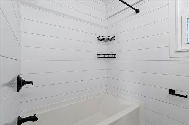 bathroom featuring wooden walls and shower / washtub combination