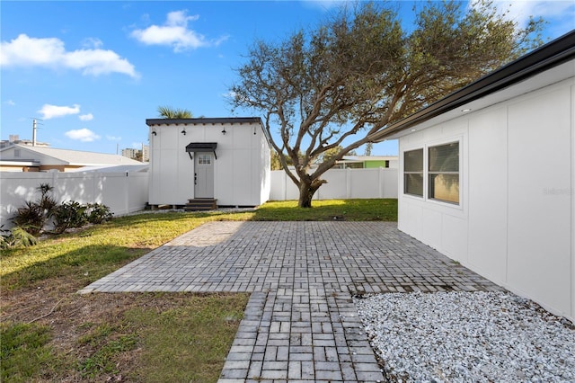 back of house featuring an outbuilding, a yard, and a patio