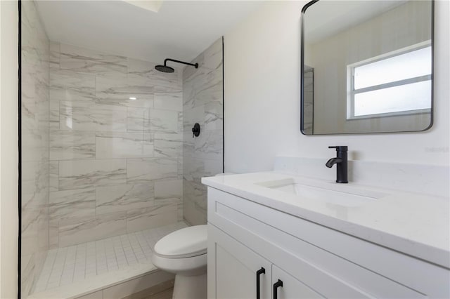 bathroom featuring toilet, a tile shower, and vanity