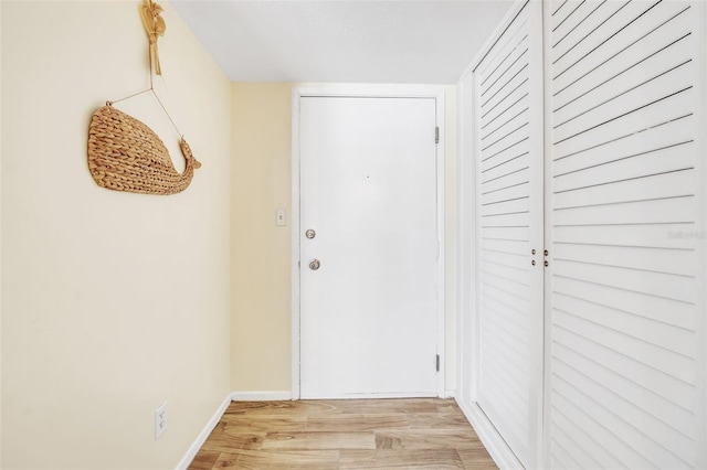 hallway featuring baseboards and light wood finished floors