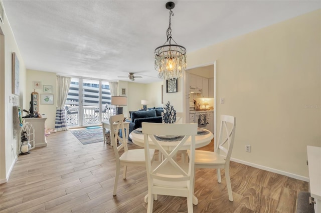 dining area featuring baseboards, light wood-style flooring, floor to ceiling windows, and ceiling fan with notable chandelier