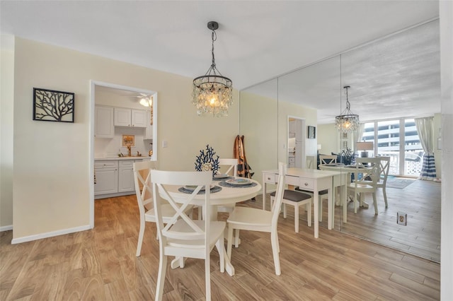 dining area with light wood finished floors, a chandelier, baseboards, and expansive windows