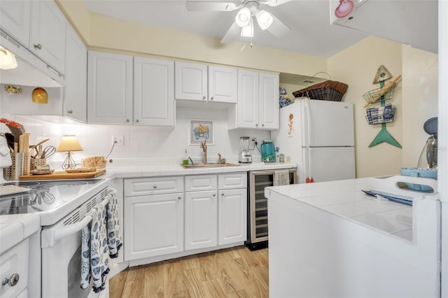 kitchen featuring wine cooler, tile countertops, light wood-style floors, white appliances, and a sink