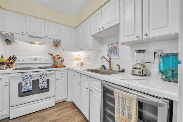 kitchen featuring under cabinet range hood, a sink, white cabinetry, white electric stove, and tile countertops