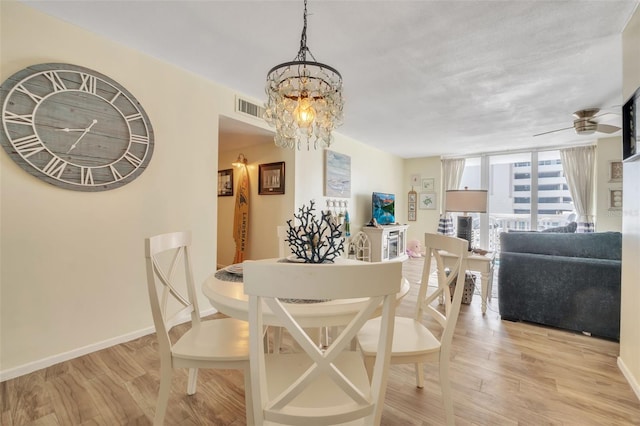 dining space featuring ceiling fan with notable chandelier, floor to ceiling windows, visible vents, and light wood-type flooring