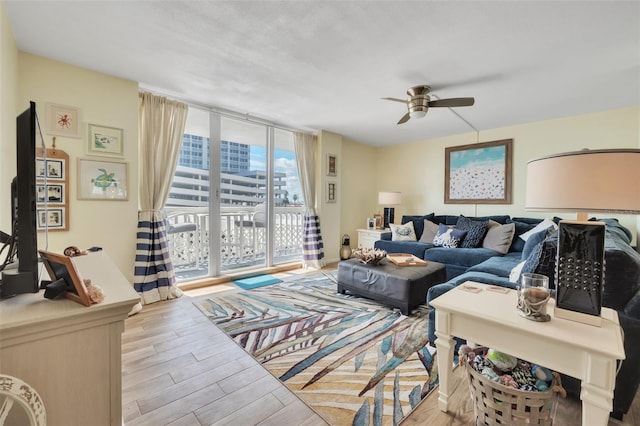 living room featuring a wall of windows, ceiling fan, and wood finished floors