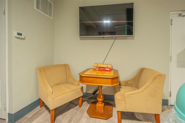 sitting room featuring visible vents, baseboards, and wood finished floors